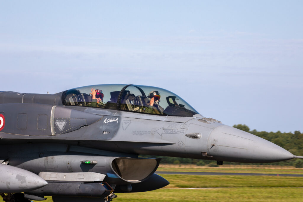 Hävituslennuk F-16 mööda maad sõitmas, õhkutõusmise eel, kaks pilooti lkäega tervitamas.